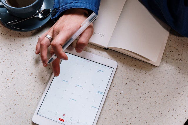 White tablet showing calendar on screen with person scheduling