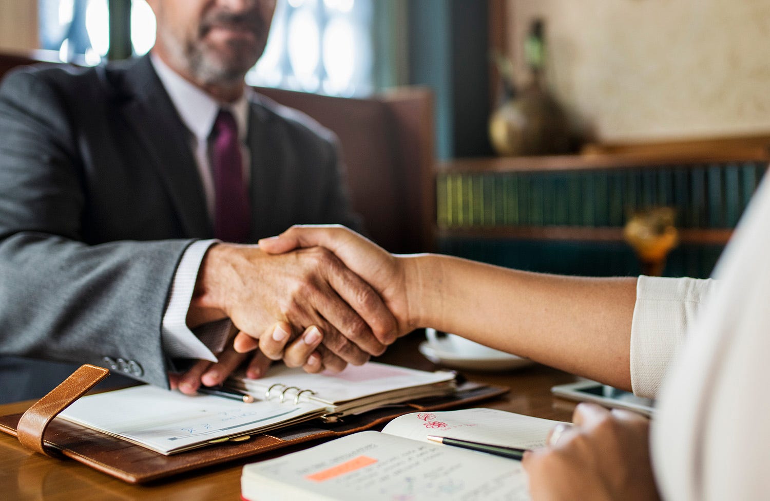 Woman and man sitting at a table and shaking hands